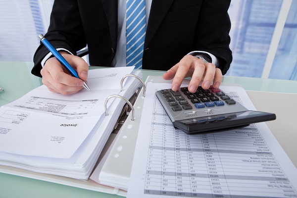 Businessman Calculating Invoice At Office Desk
